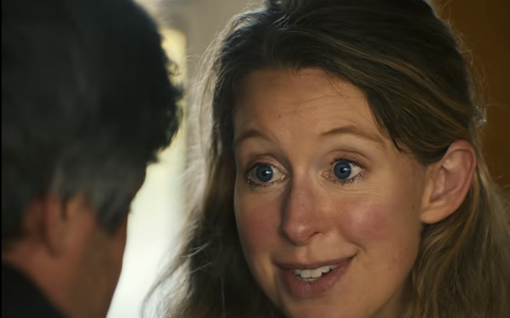 Elizabeth Holmes talking to Nathan Fielder, a still from the teaser for You Can See Everything (Nathan Fielder and Lance Oppenheim, A24, 2026).